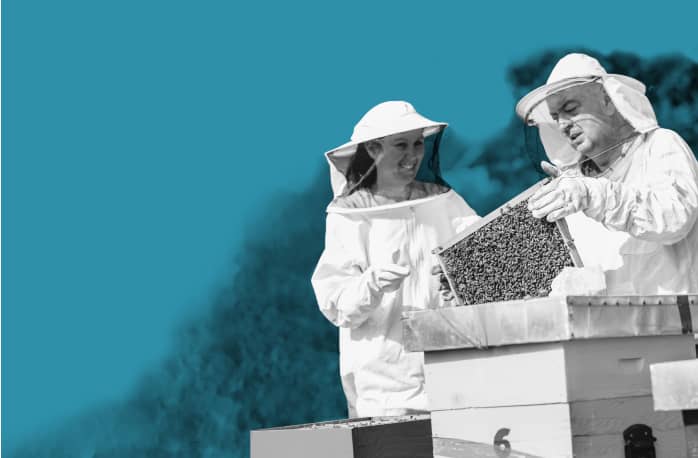 a couple of people that are standing in front of a beehive.